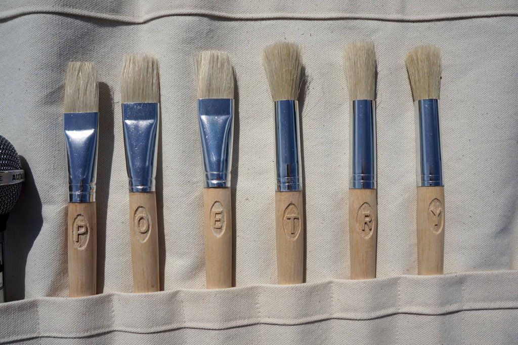 5 paintbrushes in a tool roll with the letters P O E T R Y engraved on them
